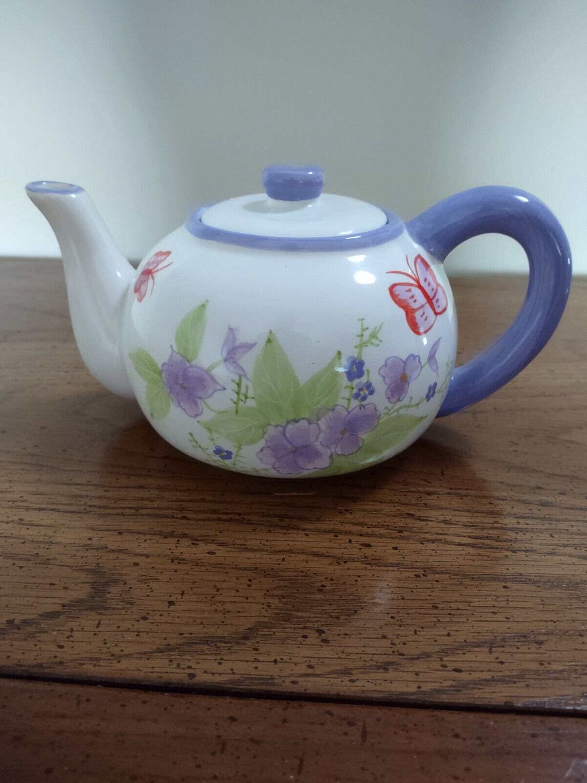 Beautiful ceramic teapot with purple flowers and butterflies