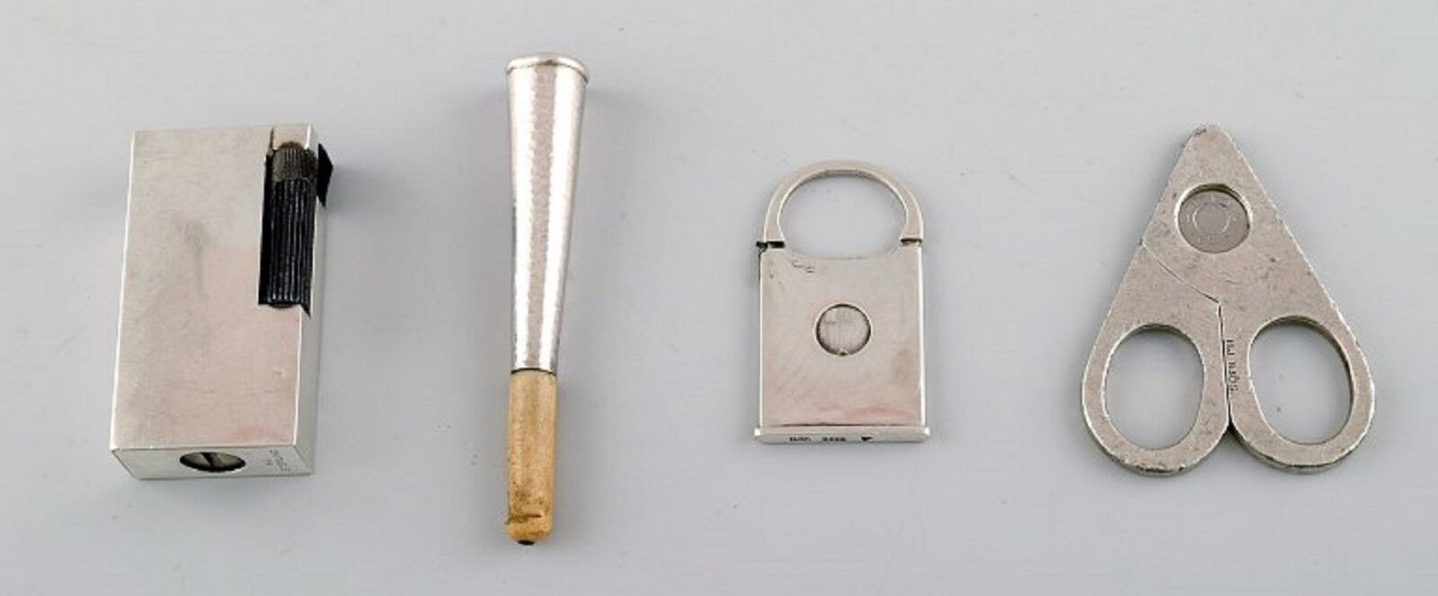 Four pieces Danish silver. Lighter, cigarette holder and two cigar clippers.