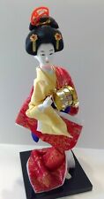 Geisha figure dressed in red, yellow, blue, and gold holding a drum. picture