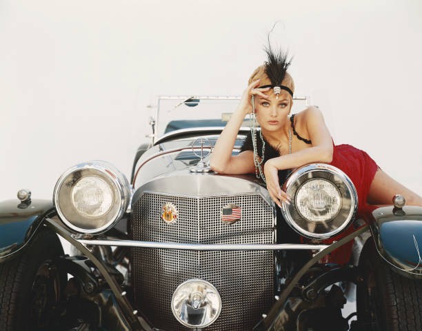 Young woman lying on vintage car portrait Historic 1960s Old Photo