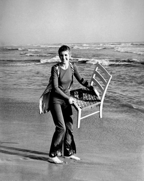 British singer Julie Driscoll raising a chair by the seashore 1960s Old Photo