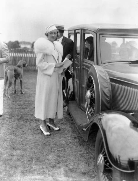 Elaine B Barry stands a field next to an automobile passengers ins- Old Photo
