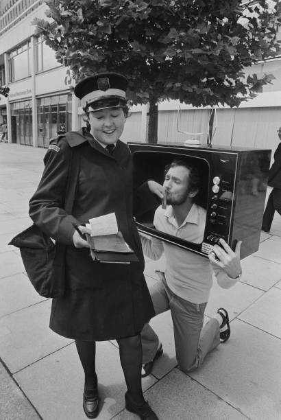 Comedian Kenny Everett kneels to kiss the hand of an amused traffi- Old Photo