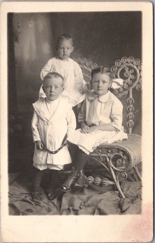 c1910s Studio Photo RPPC Postcard Two Boys & a Girl / Siblings / Wicker Chair
