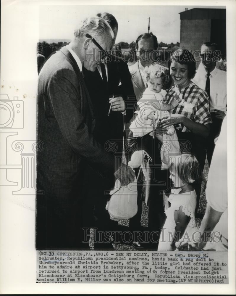 1964 Press Photo Sen. Goldwater hand rag doll back to Christia at airport