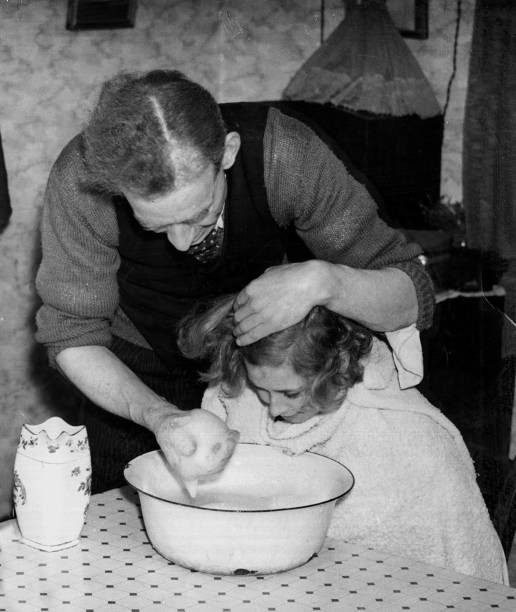 Man washing his daughter's hair face using soapy water in a bowl i- Old Photo