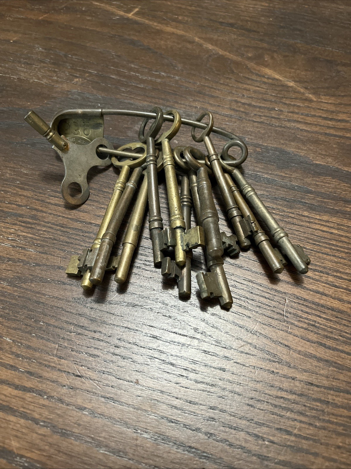 Antique lot of 11 brass skeleton keys, 1 clock wind up key on brass safety pin Antique lot of 11 brass skeleton keys, 1 clock wind up key on brass safety pin