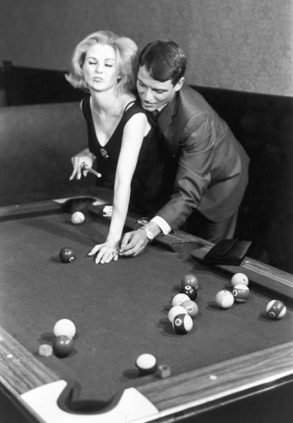 Man shows a woman how to hold a pool cue 1960s Historic 1960s Old Photo