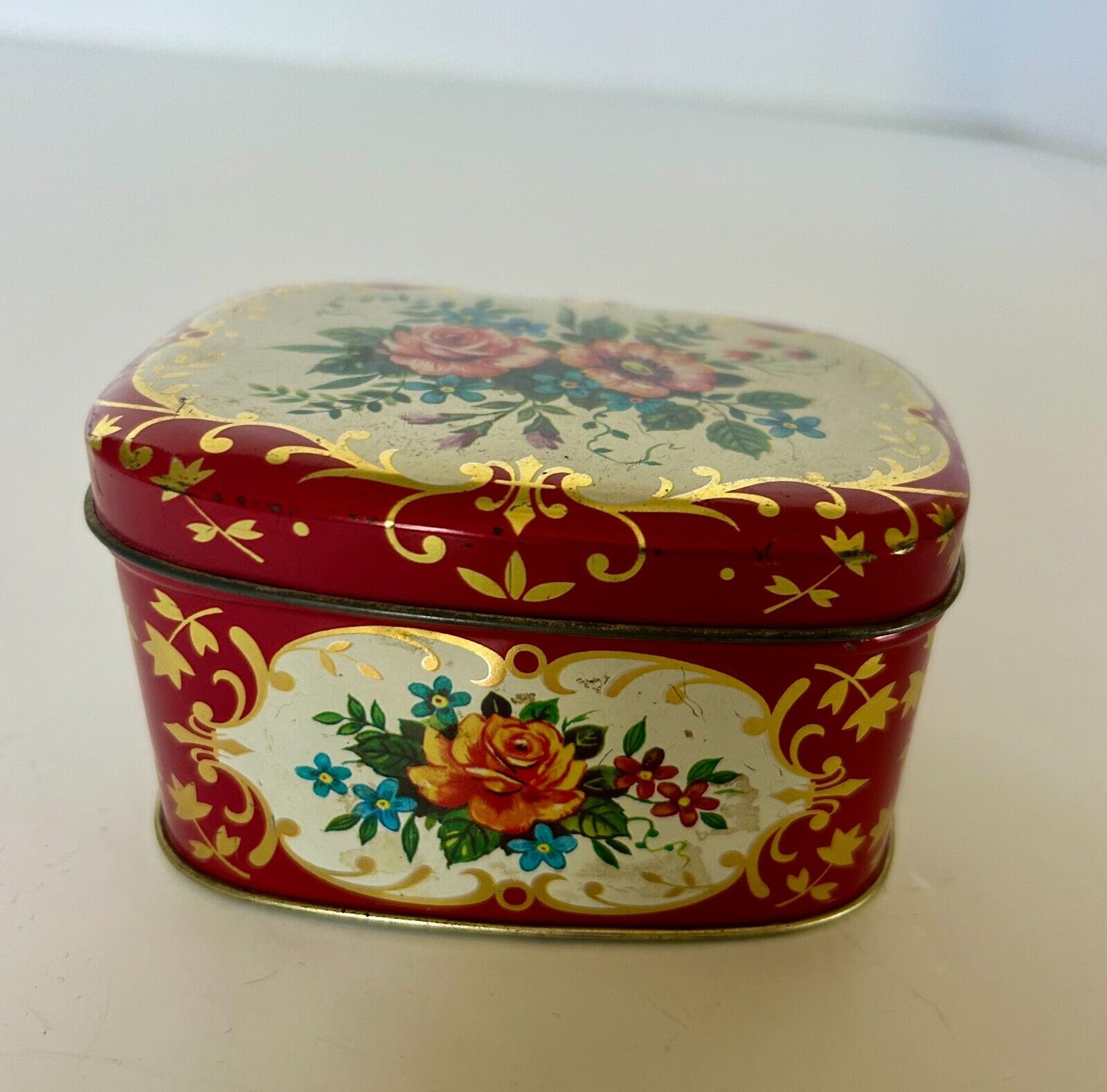 Metal trinket box made in England floral and gilt decor hinged lid rounded edges