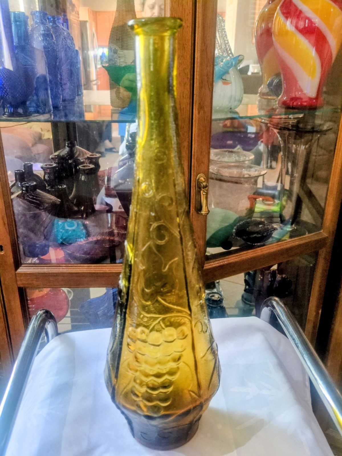 Vintage Empoli glass genie bottle with embossed fruit and leaf design.
