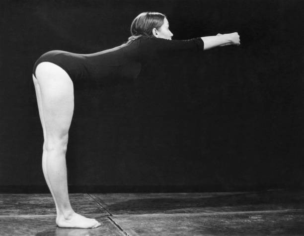 Young woman possibly a gymast dressed a leotard leans forward a st- Old Photo