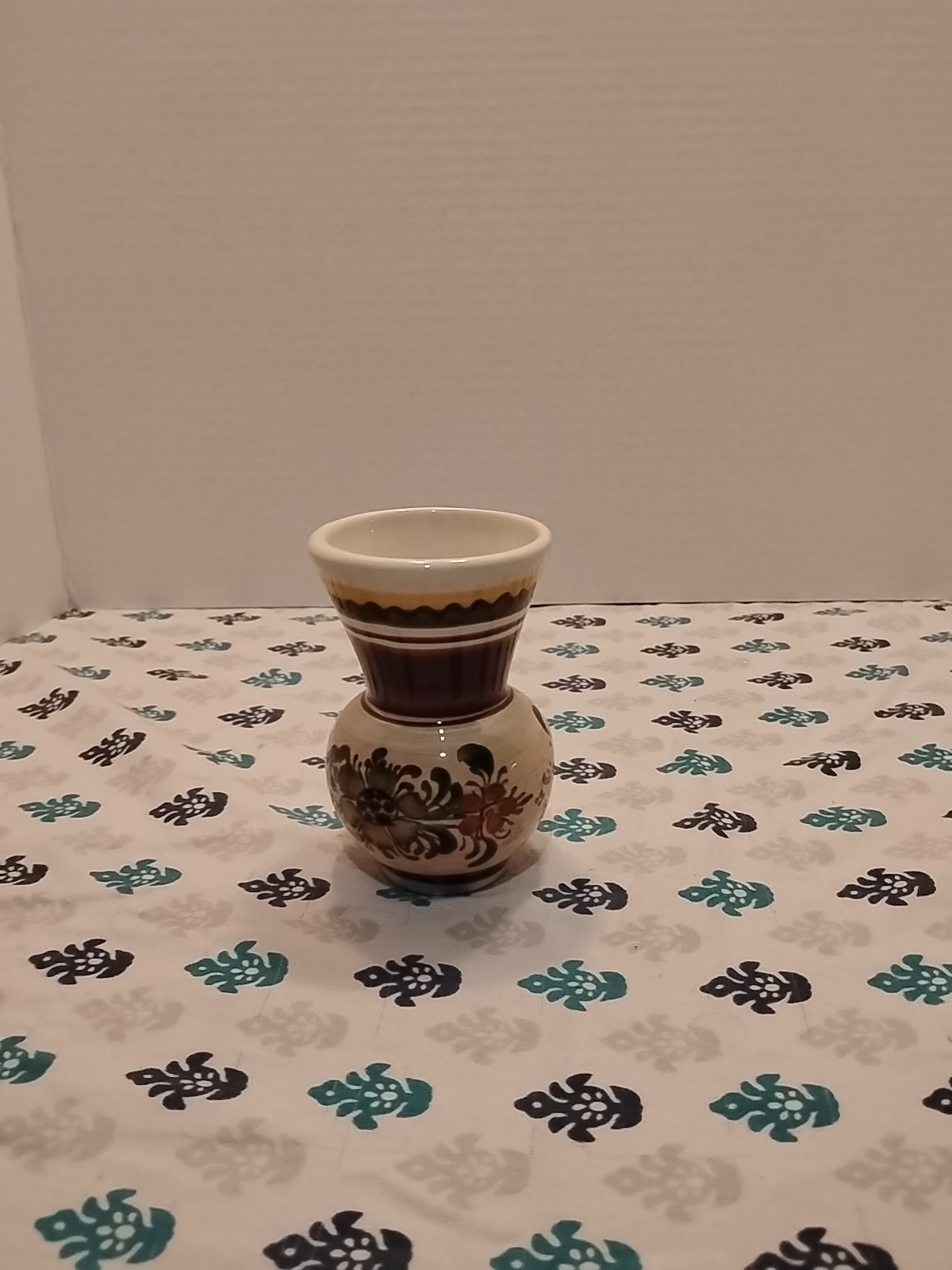 small, hand-painted ceramic vase with a floral design. small, hand-painted ceramic vase with a floral design.