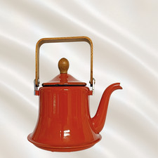 This vintage orange enamelware teapot brings a vibrant splash of retro color and picture