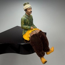 A vintage figurine of a seated Uzbek man, crafted from ceramic and fabric—a piec picture